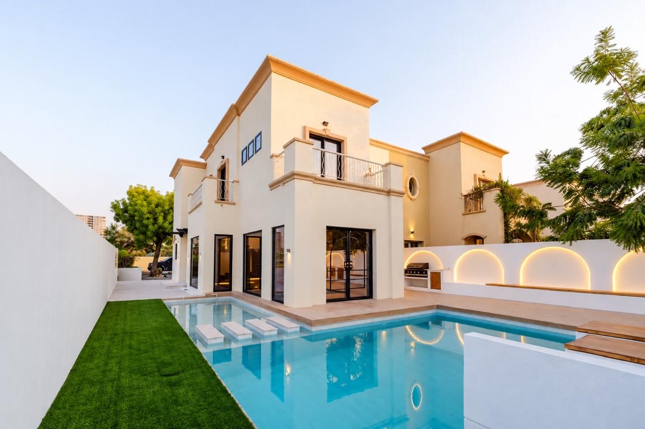 Renovated Dubai villa with new swimming pool, lawn and illuminated arched garden wall at dusk