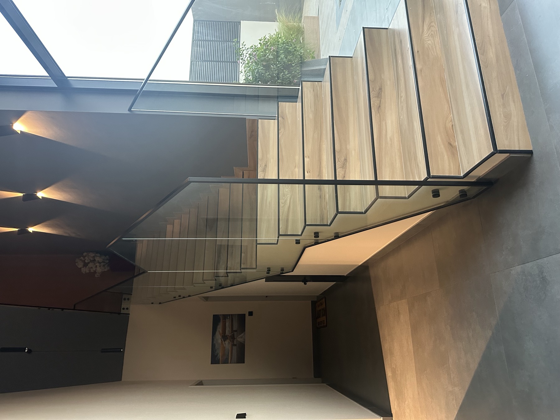 Oak staircase with structural glass balustrade and black steel nosing