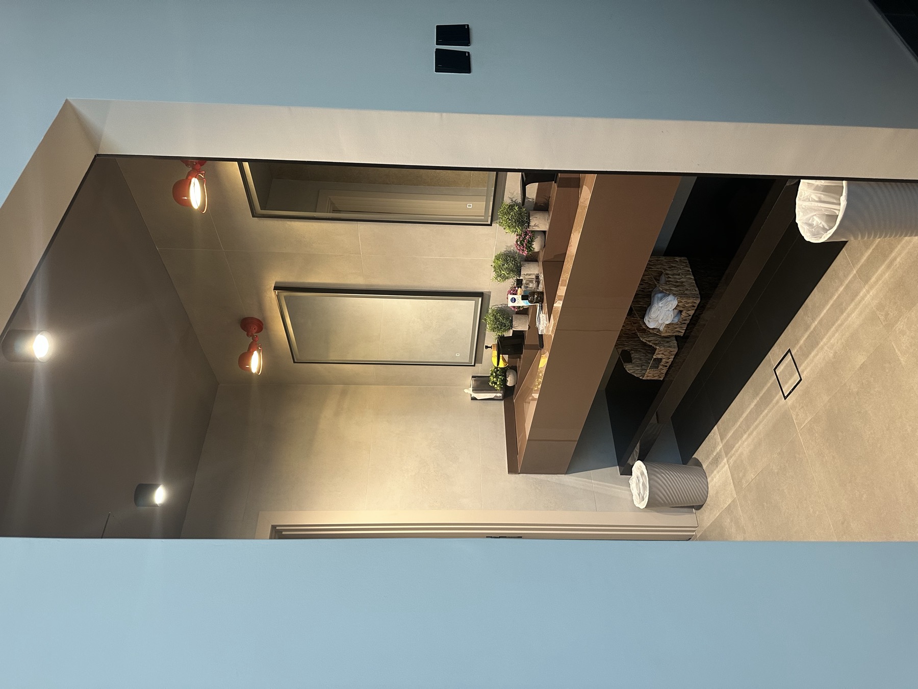 Double vanity with bronze mirrors, wall lighting and a floating counter