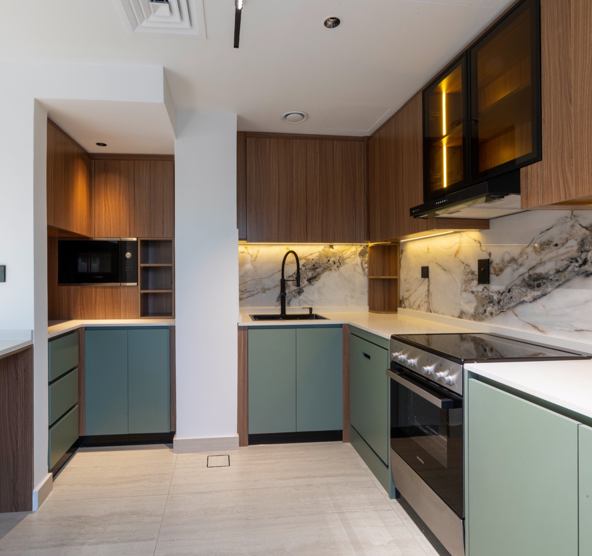 Bespoke kitchen in sage green and walnut with marble-effect backsplash and integrated appliances