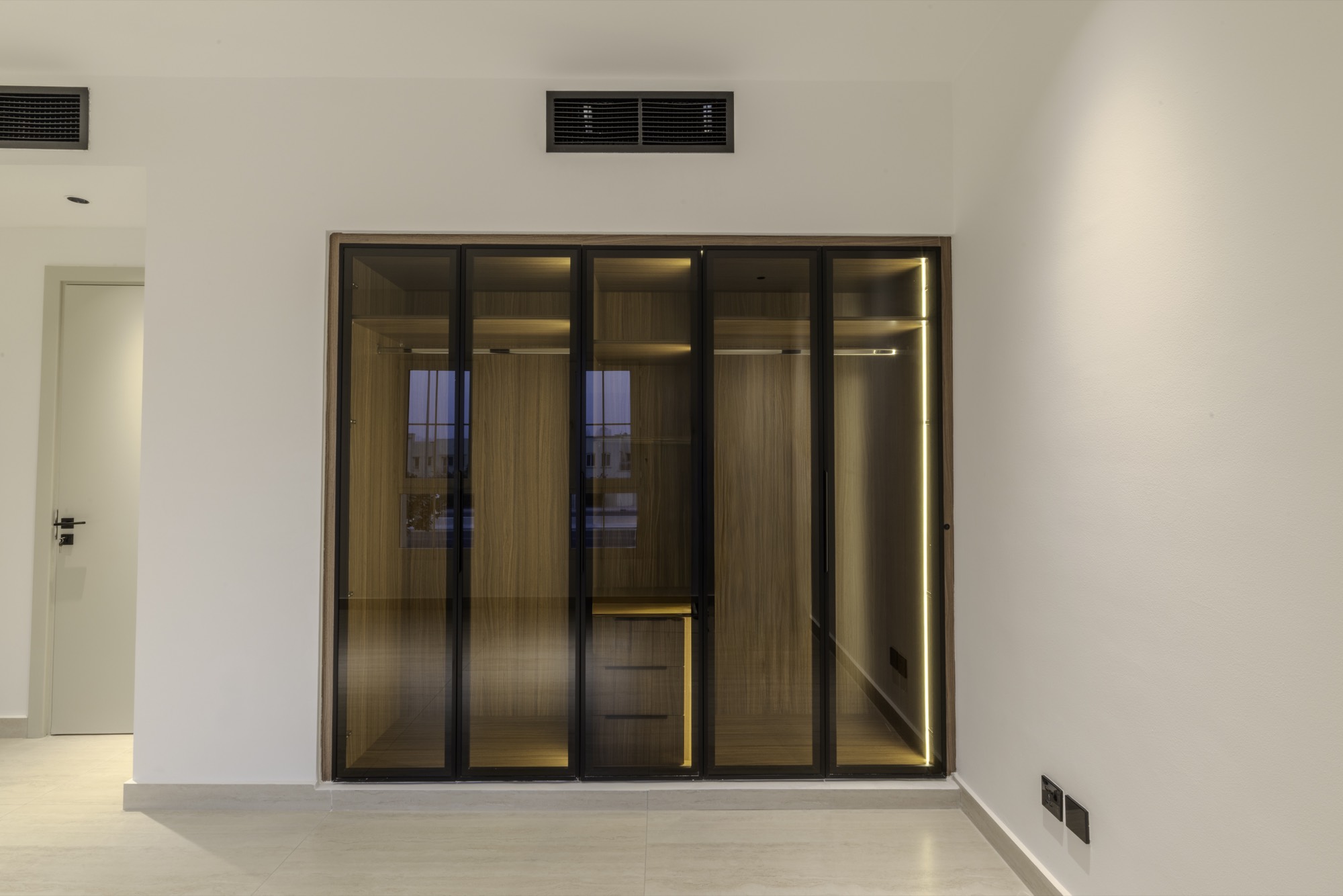 Built-in wardrobe with bronze glass doors, oak interior and integrated lighting